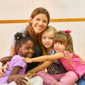 Children and caretaker happily smiles and hugs each other